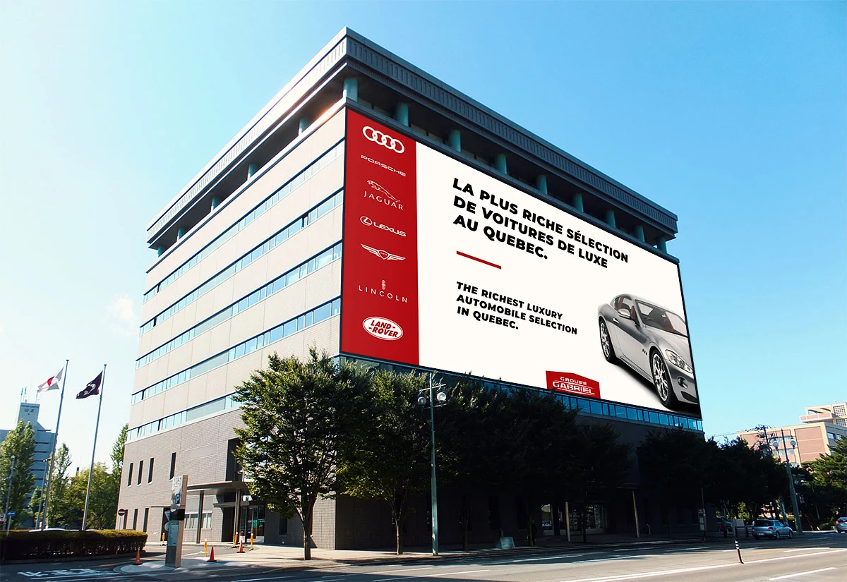 The building wrap — a red column carrying the Audi, Porsche, Jaguar, Lexus, Genesis, Lincoln and Land Rover badges beside the luxury selection claim.