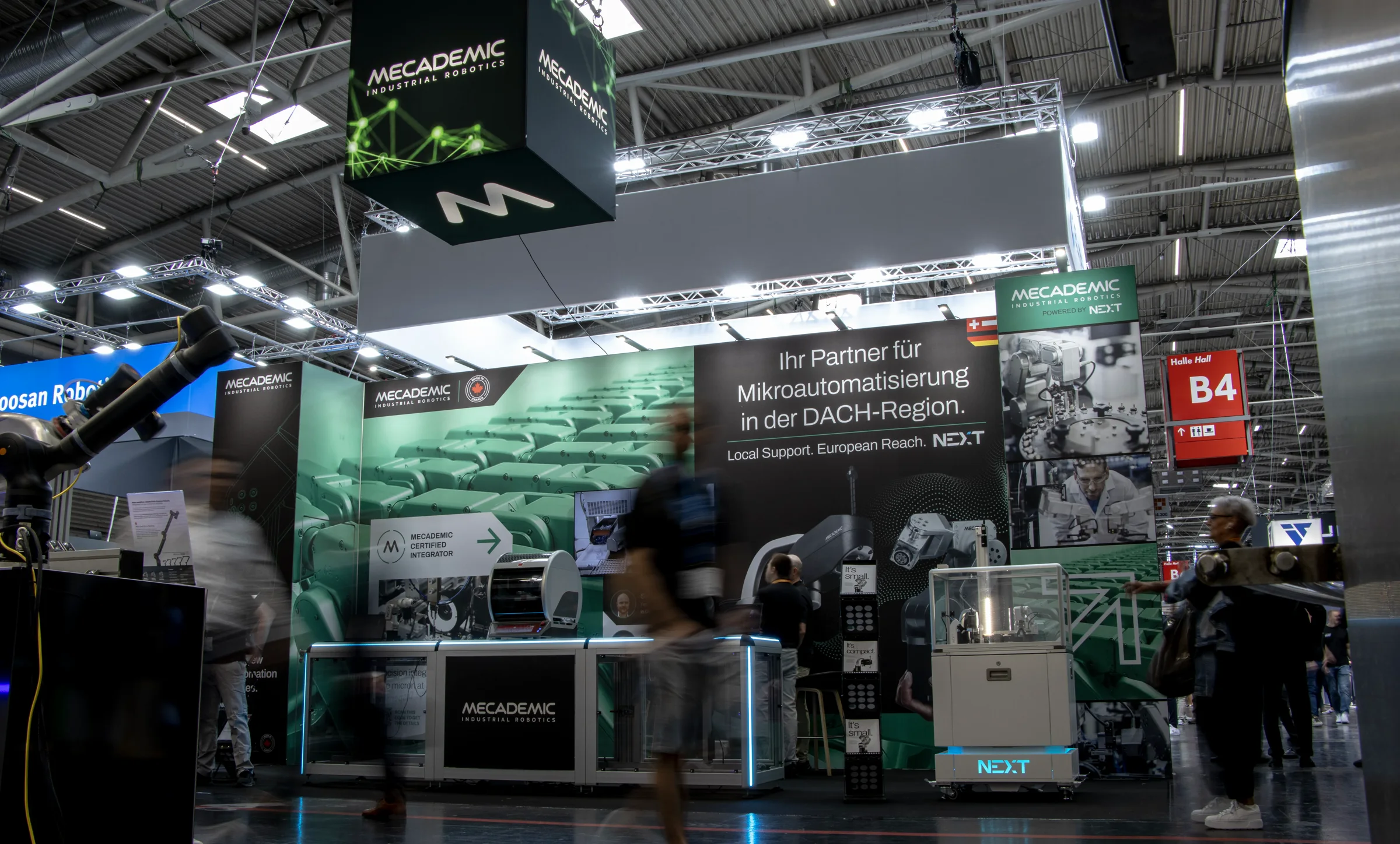 The stand built and open at Automatica 2025 in Munich, visitors moving in front of the wall.