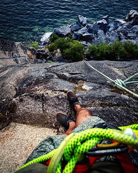 Looking down past climbing shoes to the lake at the base of the wall.