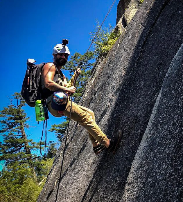 Alex rappelling down a cliff face in the Okanagan, camera rigged to his helmet and pack.